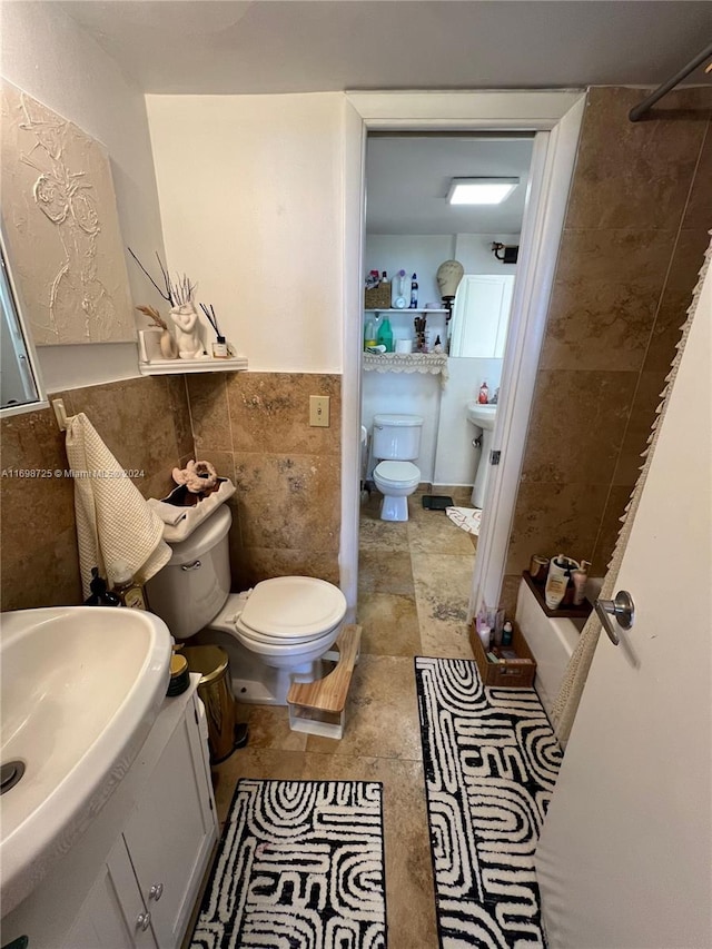 bathroom with vanity, toilet, tile walls, and walk in shower