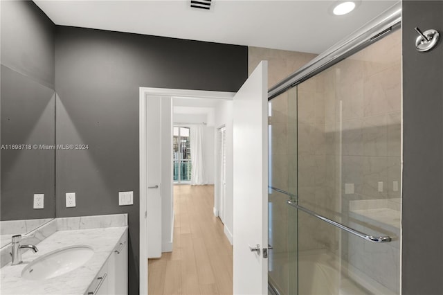 bathroom with vanity, wood-type flooring, and combined bath / shower with glass door