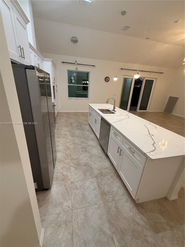 kitchen with light stone counters, white cabinets, vaulted ceiling, and appliances with stainless steel finishes