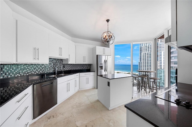 kitchen with a kitchen island, decorative light fixtures, a water view, white cabinets, and appliances with stainless steel finishes