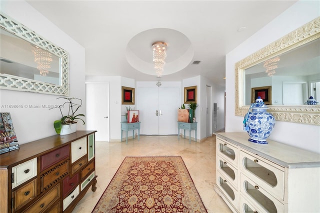 entrance foyer featuring a raised ceiling and a notable chandelier