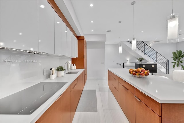 kitchen with white cabinetry, sink, a spacious island, decorative light fixtures, and light tile patterned floors