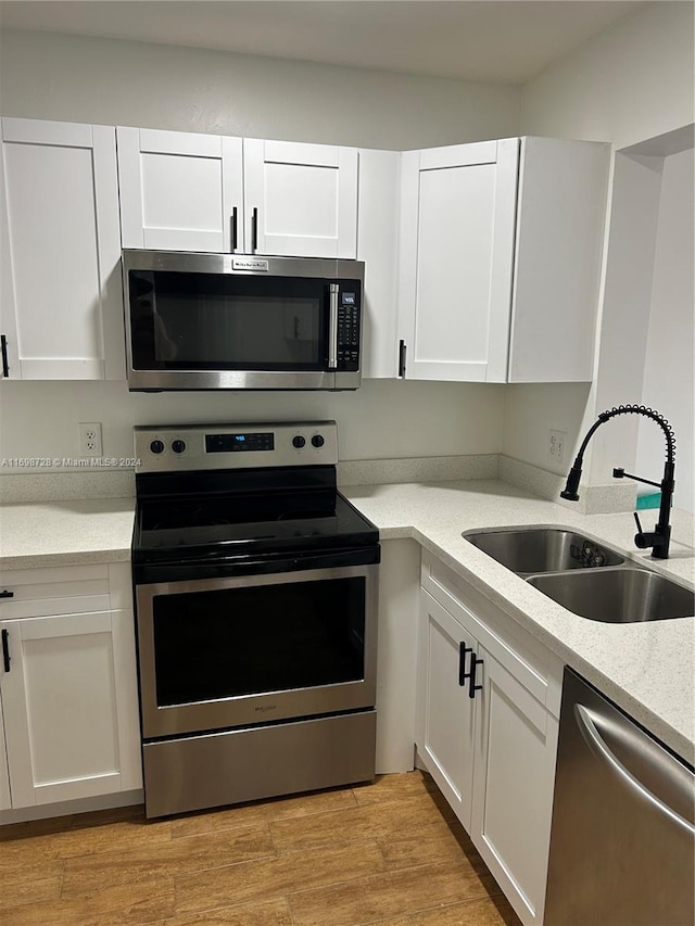 kitchen with light hardwood / wood-style flooring, stainless steel appliances, white cabinetry, and sink