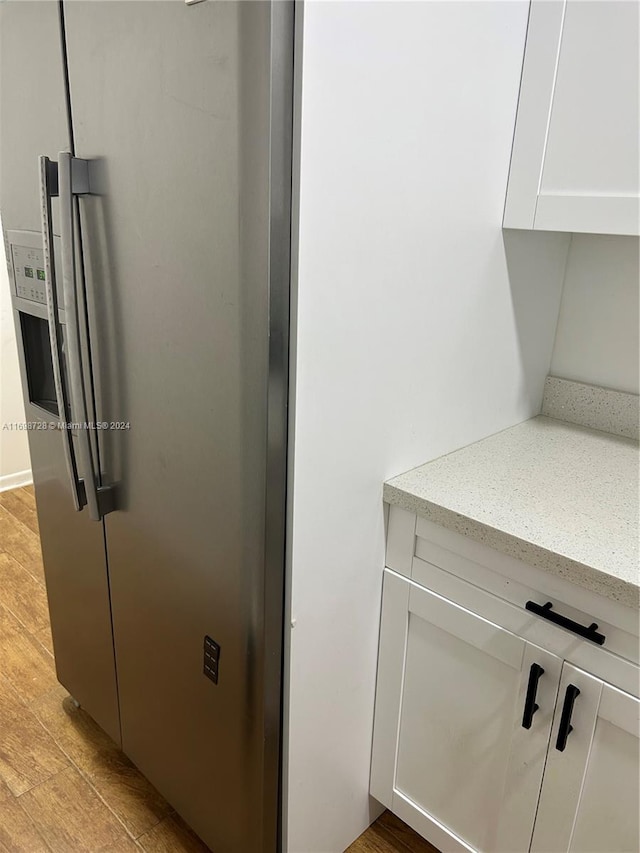 interior details featuring white cabinetry, stainless steel fridge, and light hardwood / wood-style flooring