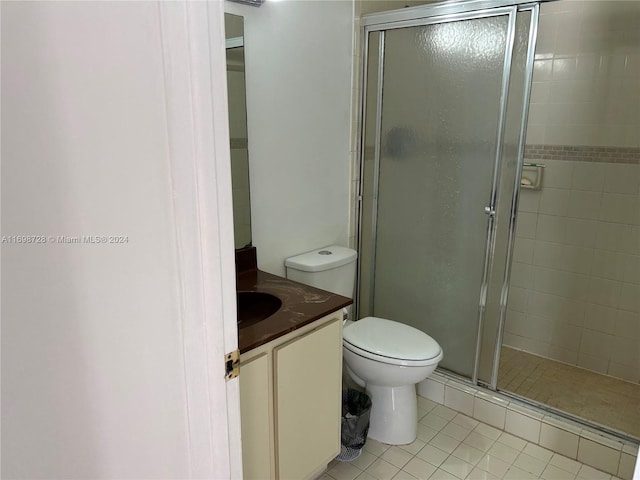 bathroom featuring tile patterned flooring, vanity, a shower with shower door, and toilet