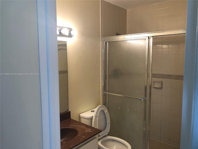 bathroom featuring vanity, toilet, and a shower with shower door