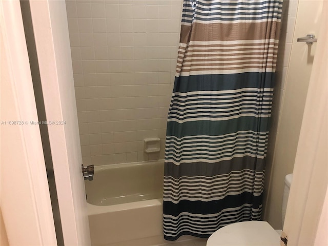 bathroom with shower / bath combination with curtain and toilet