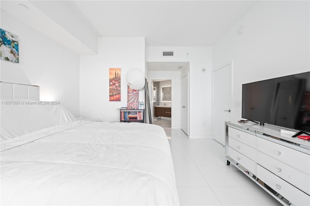 bedroom featuring ensuite bathroom and light tile patterned flooring