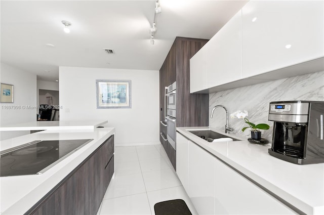 kitchen with backsplash, white cabinets, sink, black electric cooktop, and dark brown cabinets