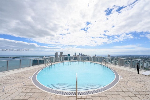 view of pool featuring a patio and a water view