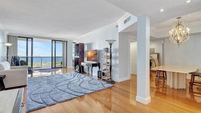 living room featuring expansive windows, ornamental molding, light hardwood / wood-style floors, a water view, and an inviting chandelier