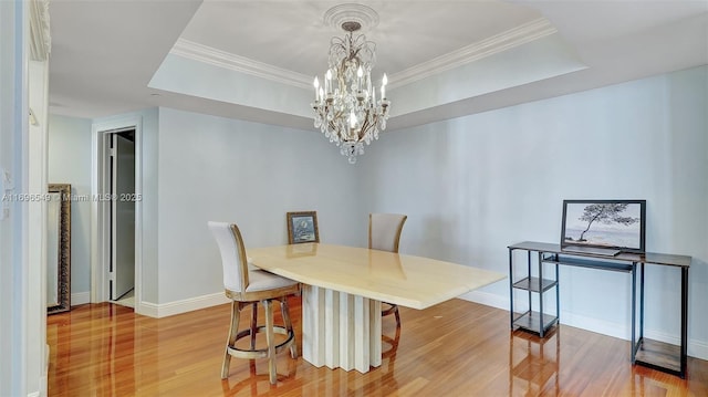 dining space with a notable chandelier, crown molding, and a raised ceiling