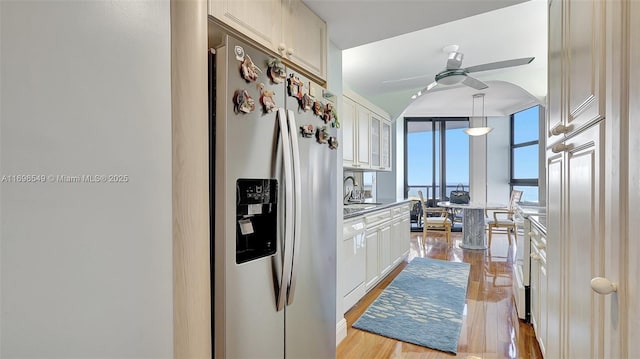 kitchen featuring a wall of windows, white cabinetry, stainless steel fridge with ice dispenser, decorative light fixtures, and light wood-type flooring