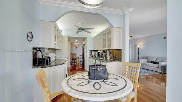 dining space featuring ceiling fan, ornamental molding, sink, and light wood-type flooring