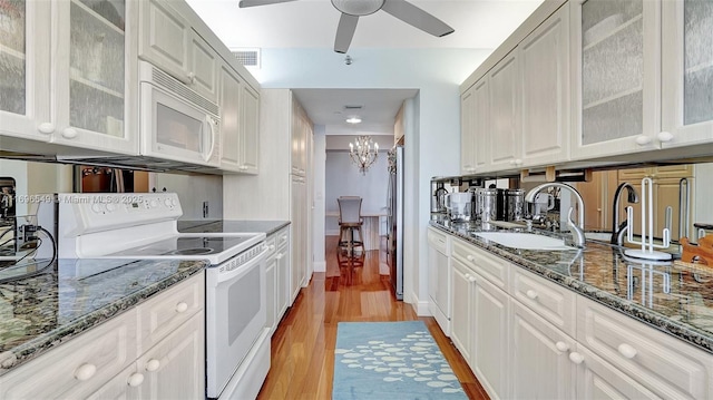 kitchen featuring white cabinetry, sink, white appliances, and dark stone countertops