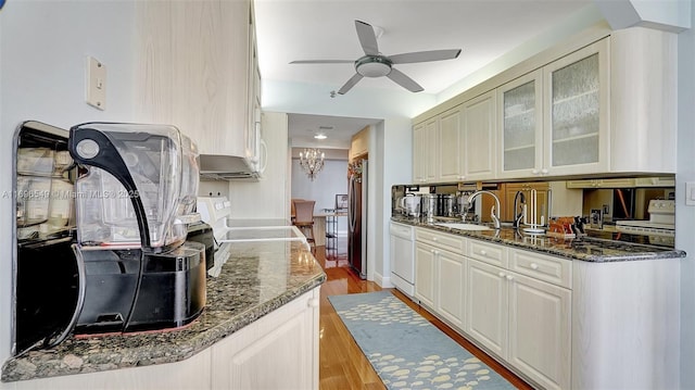 kitchen featuring sink, dark stone countertops, stainless steel fridge, ceiling fan, and light hardwood / wood-style flooring