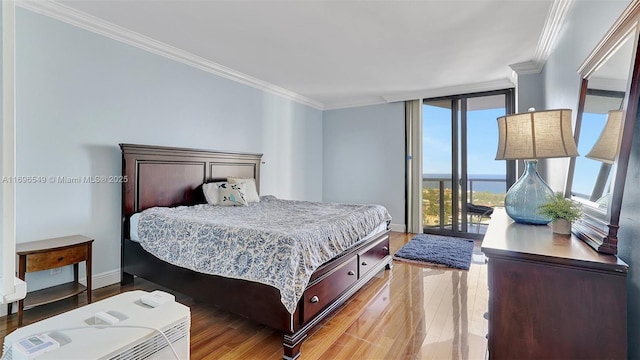 bedroom featuring hardwood / wood-style floors, a wall of windows, ornamental molding, access to outside, and a water view