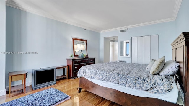 bedroom with light hardwood / wood-style flooring, ornamental molding, and a closet