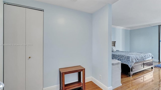 bedroom featuring hardwood / wood-style flooring, ornamental molding, and a closet