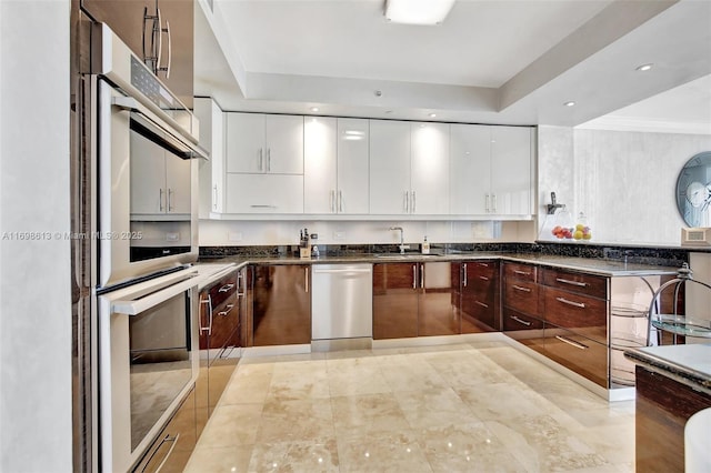 kitchen with a raised ceiling, sink, dark brown cabinets, white cabinetry, and stainless steel appliances