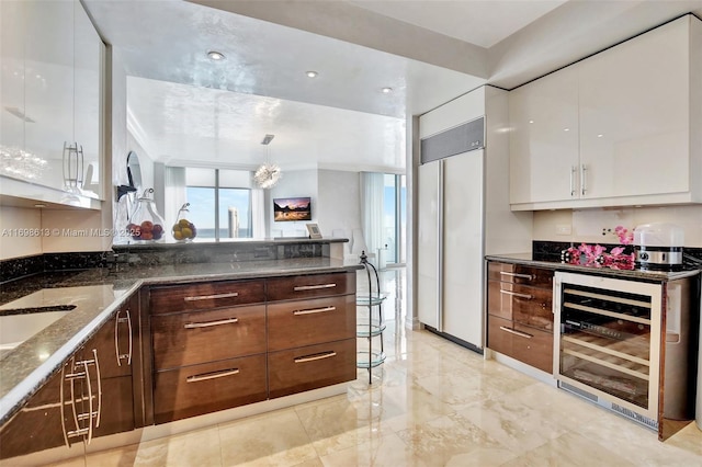 kitchen featuring white cabinetry, beverage cooler, paneled refrigerator, dark stone counters, and pendant lighting