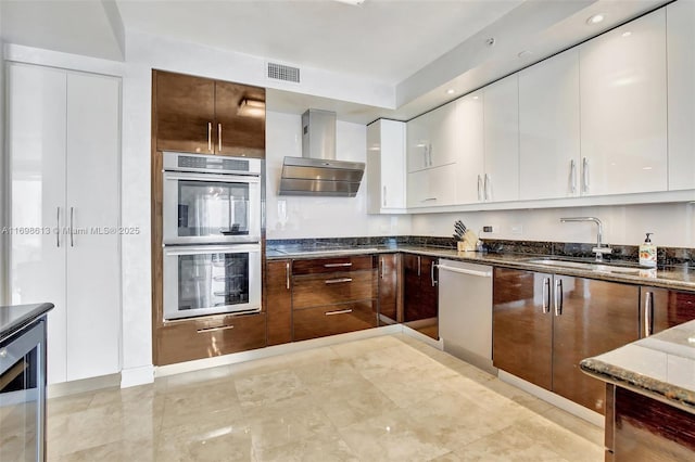 kitchen featuring sink, wall chimney exhaust hood, white cabinetry, stainless steel appliances, and beverage cooler