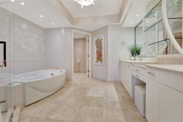 bathroom featuring a raised ceiling, a tub, and vanity