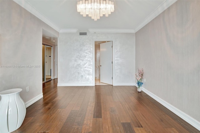 empty room featuring crown molding, hardwood / wood-style flooring, and a notable chandelier