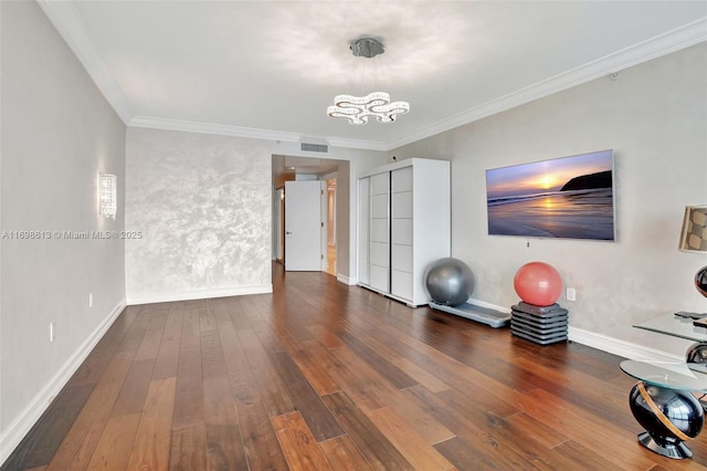 workout area with dark hardwood / wood-style flooring, ornamental molding, and a chandelier