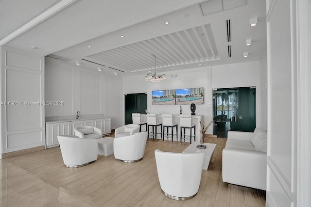 living room with beam ceiling, light hardwood / wood-style flooring, and an inviting chandelier