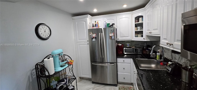 kitchen featuring stainless steel fridge, white cabinetry, sink, and tasteful backsplash