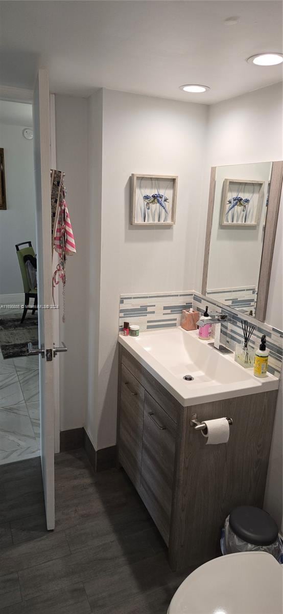 bathroom featuring wood-type flooring, vanity, tasteful backsplash, and toilet