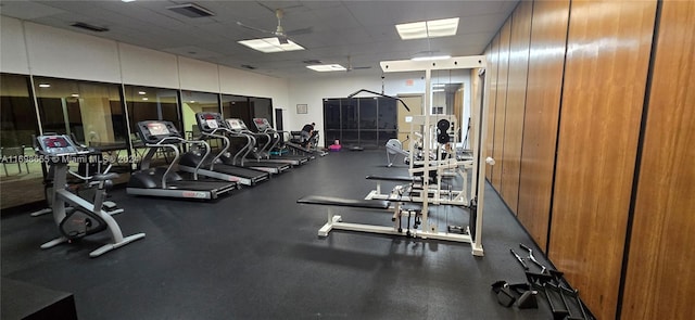 gym with a paneled ceiling and ceiling fan