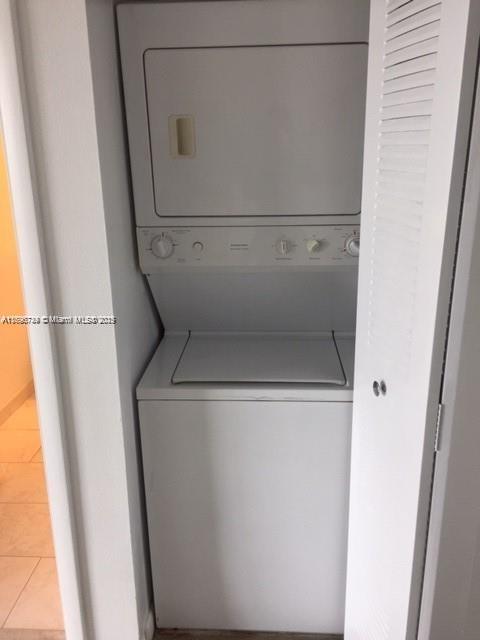 laundry room featuring stacked washer / dryer and light tile patterned floors