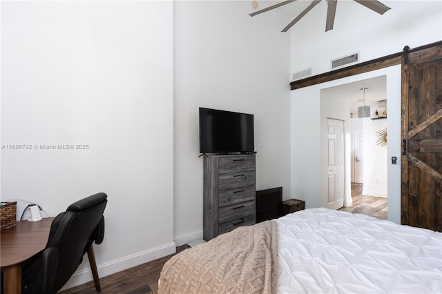 bedroom featuring a barn door, ceiling fan, and wood-type flooring