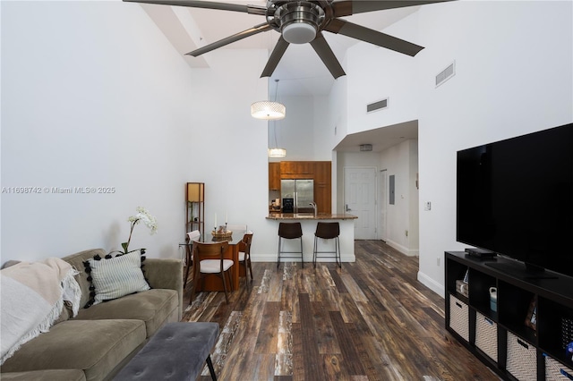 living room featuring ceiling fan, sink, a towering ceiling, and dark hardwood / wood-style floors