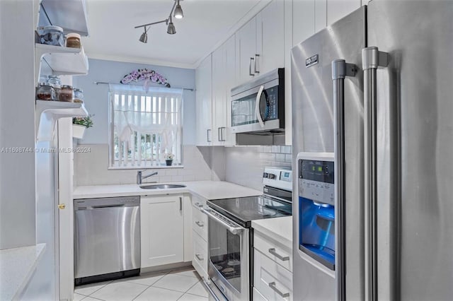 kitchen featuring backsplash, white cabinets, sink, light tile patterned floors, and stainless steel appliances