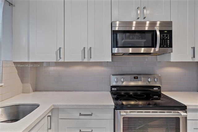 kitchen with appliances with stainless steel finishes, tasteful backsplash, and white cabinetry