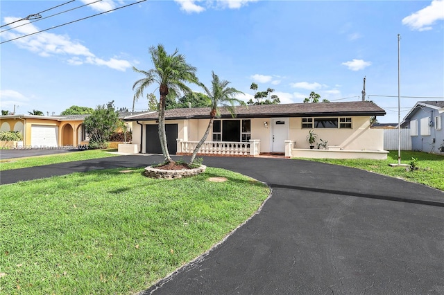 ranch-style home with a front lawn, covered porch, and a garage