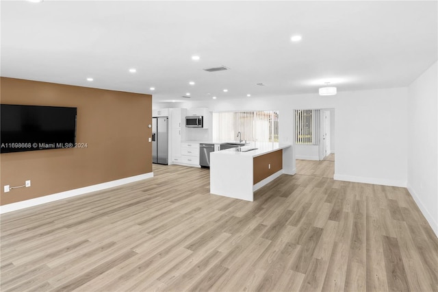 kitchen featuring light wood-type flooring, stainless steel appliances, and white cabinetry