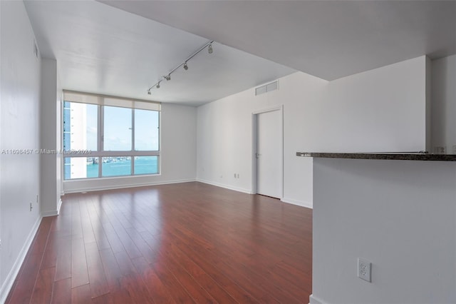 unfurnished room featuring a water view, rail lighting, and dark hardwood / wood-style floors