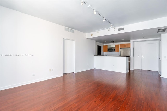 unfurnished living room featuring rail lighting and dark wood-type flooring