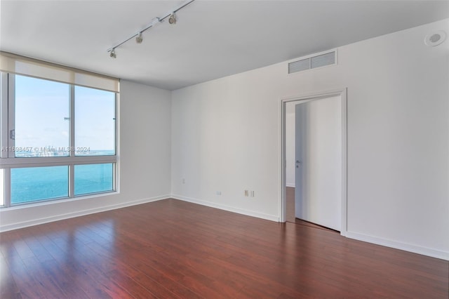 unfurnished room featuring track lighting and dark hardwood / wood-style floors