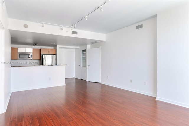 unfurnished living room featuring dark hardwood / wood-style flooring and rail lighting