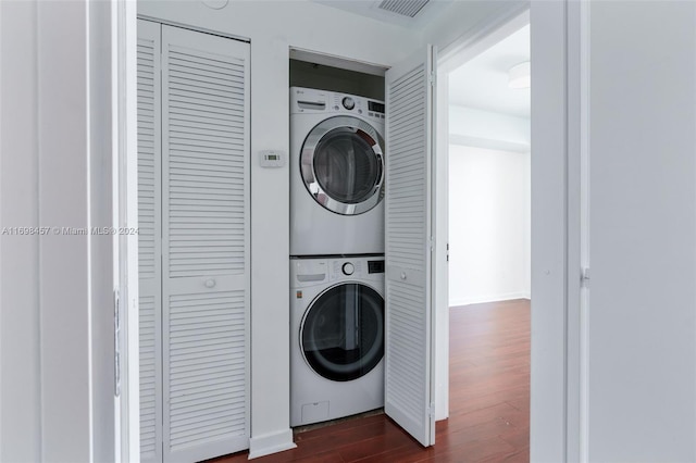 clothes washing area featuring dark hardwood / wood-style flooring and stacked washer / dryer