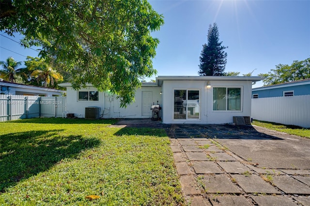 rear view of property with central AC unit, a patio area, and a lawn