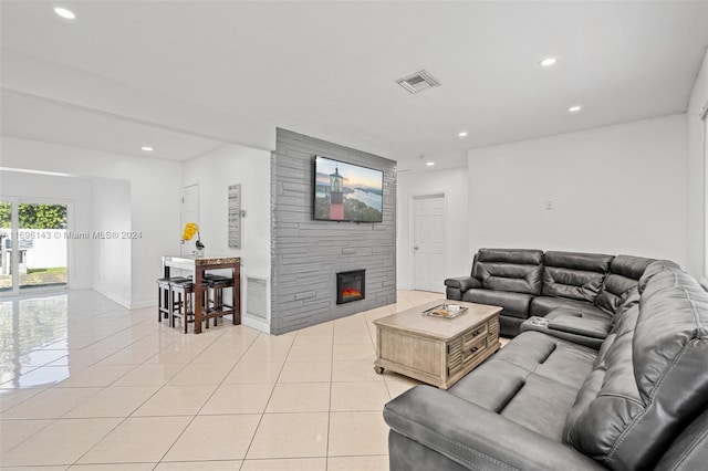 living room featuring a stone fireplace and light tile patterned flooring