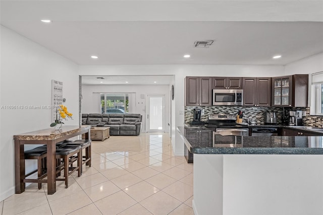 kitchen featuring backsplash, dark brown cabinetry, stainless steel appliances, and light tile patterned floors