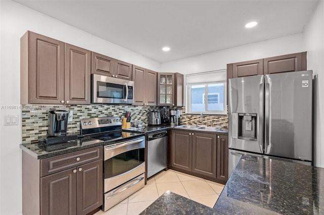 kitchen with sink, decorative backsplash, light tile patterned floors, appliances with stainless steel finishes, and dark brown cabinetry