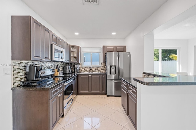 kitchen featuring backsplash, sink, dark brown cabinets, light tile patterned flooring, and stainless steel appliances